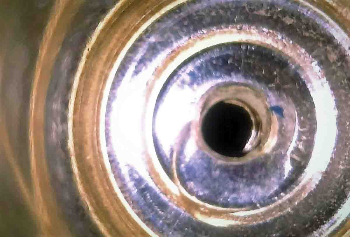 Borescopes can come in handy in any small, enclosed space. This is the inside of the flash hole on a new .257 Roberts case, showing the irregularities common with a punched hole. The line curving from the left side of the hole is a sliver of still attached brass.